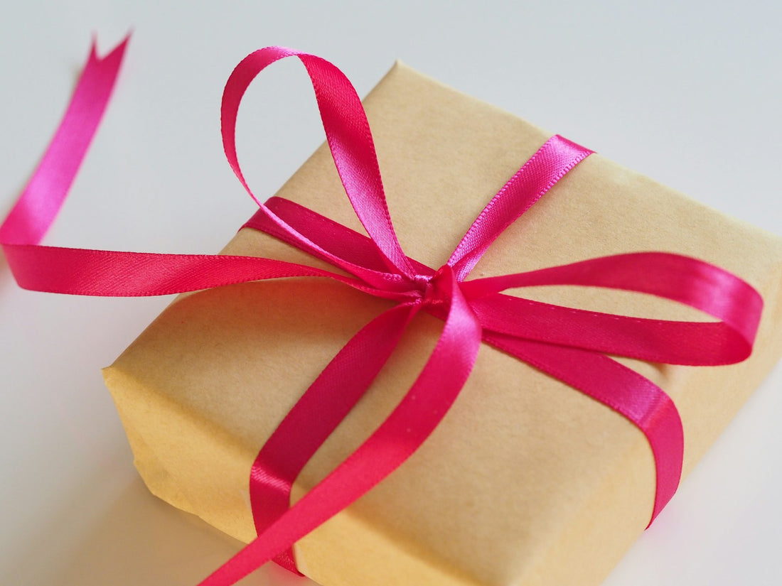 An elegantly wrapped gift box with a pink ribbon, evoking the care of choosing a fragrance gift